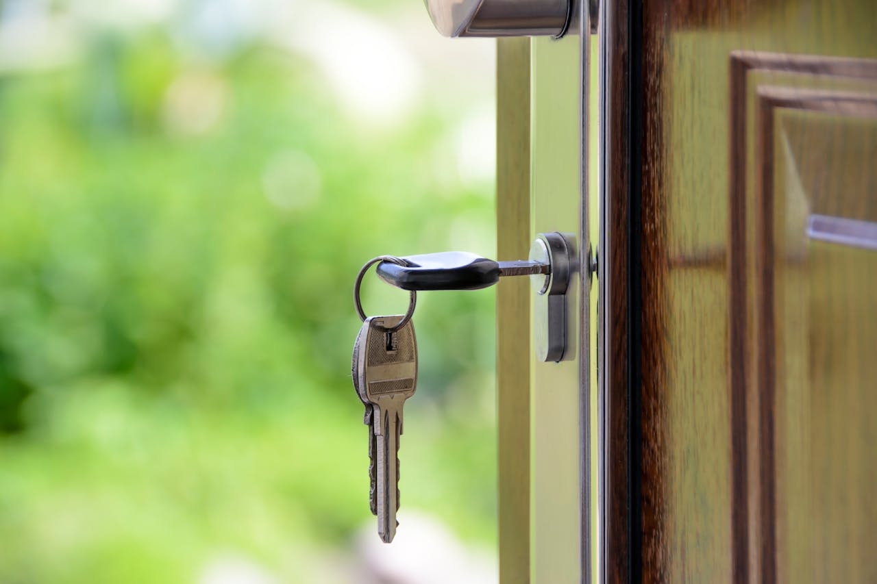 about-us Key inserted in door lock against a blurred green background, symbolizing security and real estate.